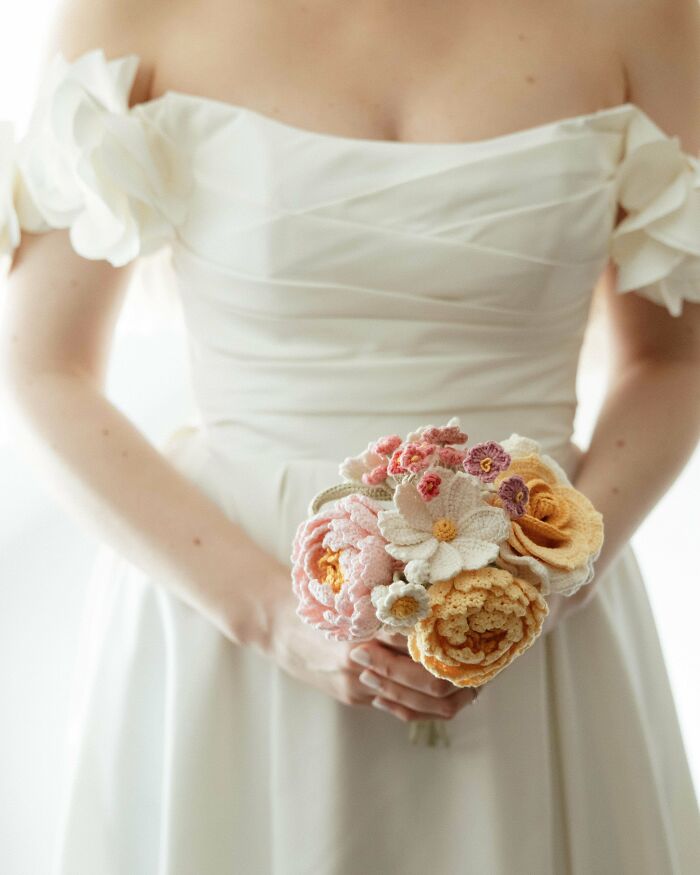 Bride holding crochet flower bouquet in white off-shoulder dress