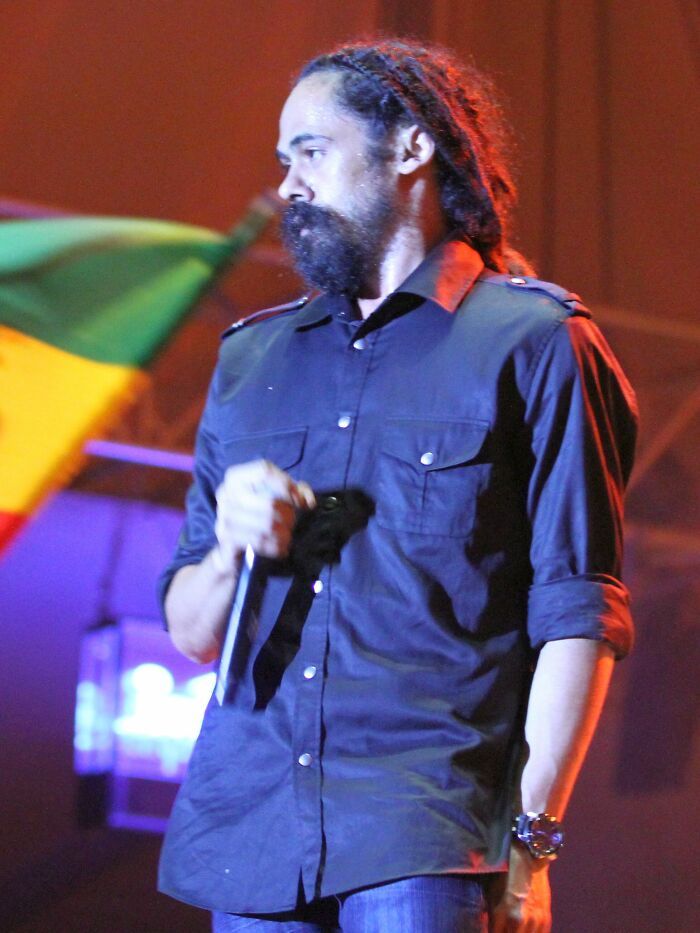 Damian Marley performs live, showcasing his career highlights and musical passion with a microphone in hand.