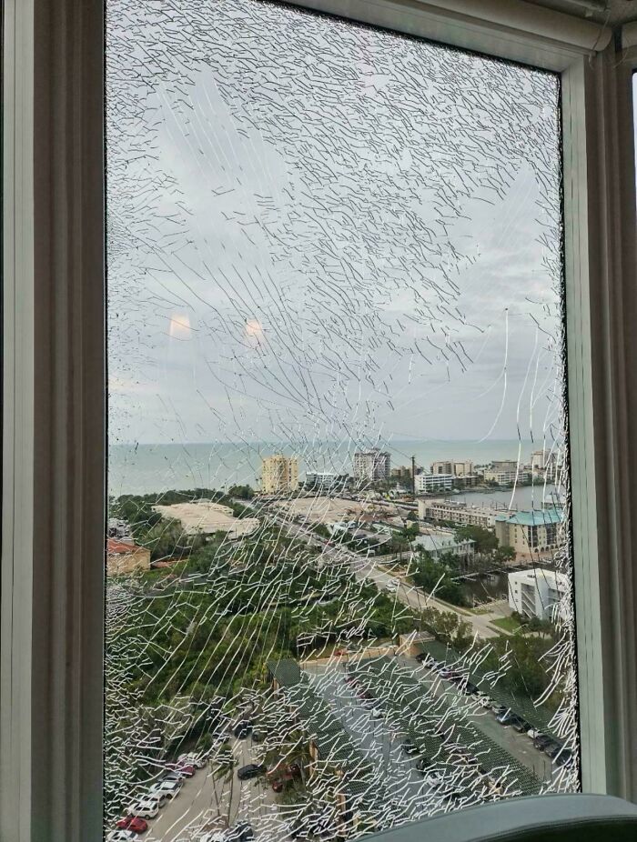 A shattered window looking out onto a cityscape and ocean, needing help fixing things and finding answers to problems.