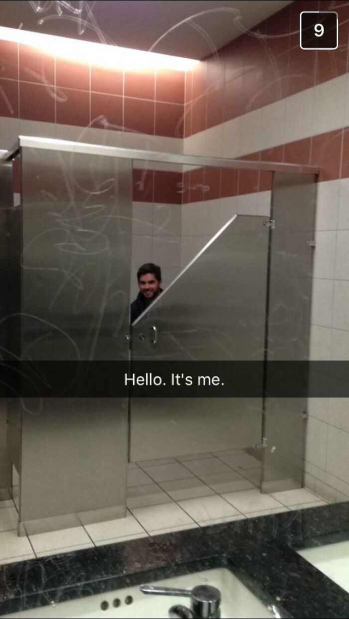 A construction fail: a man peers through the gaps of a poorly installed, reflective public restroom stall door.