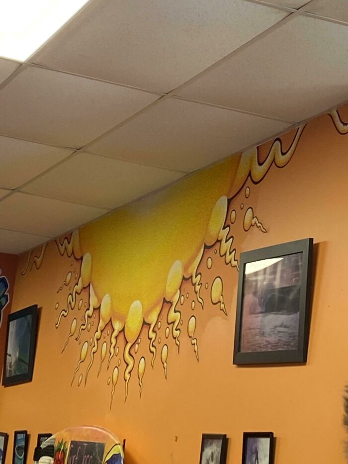 A restaurant wall mural with yellow s***m-like shapes against an orange background, showing a construction fail.