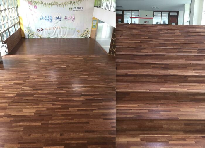 A large room with wooden floor planks that continue up a short set of stairs, a unique construction fail.