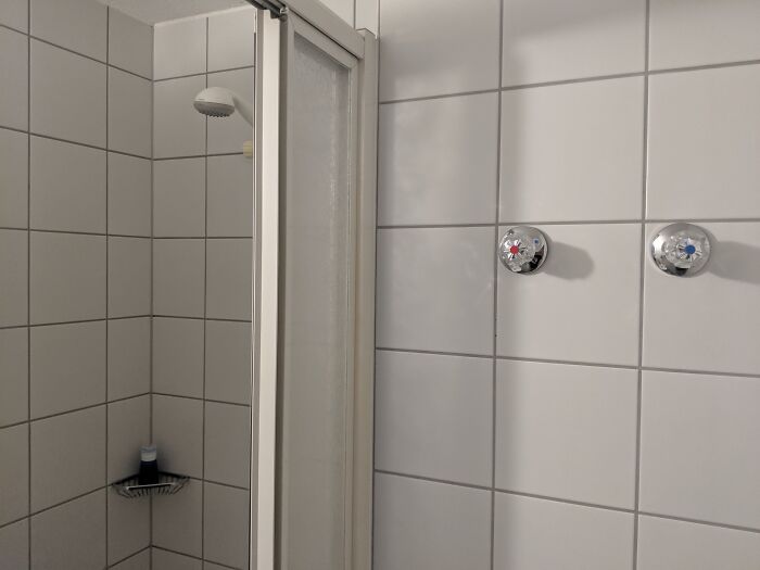 Shower handles placed on the wall outside the shower enclosure, a clear construction fail.