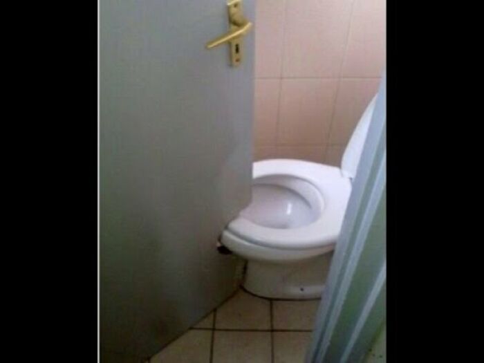 A toilet partially blocked by a door, illustrating one of many construction fails due to poor planning.