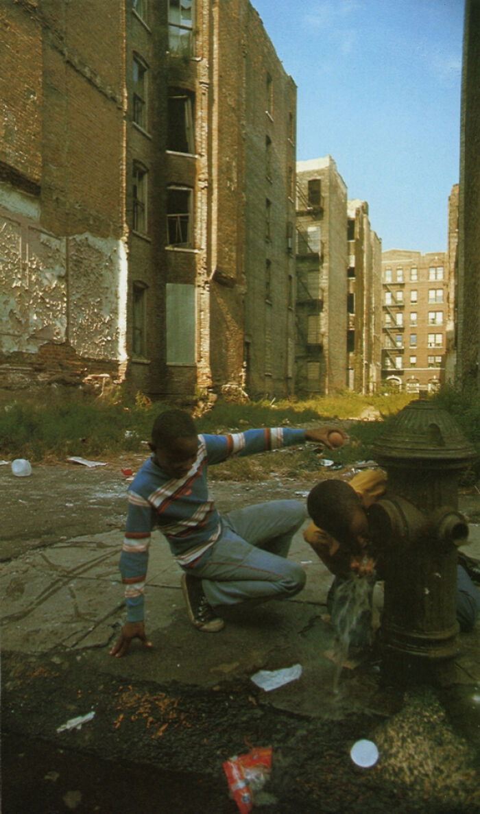 Historical photos: Two boys playing with a fire hydrant amidst crumbling buildings, showing a past that will remain alive.