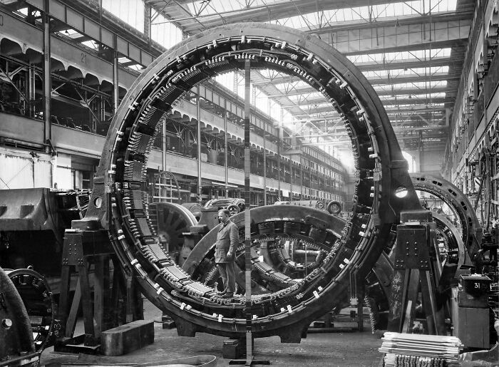 Historical photo of a man standing inside a massive industrial machine rotor, showcasing the scale of past engineering.