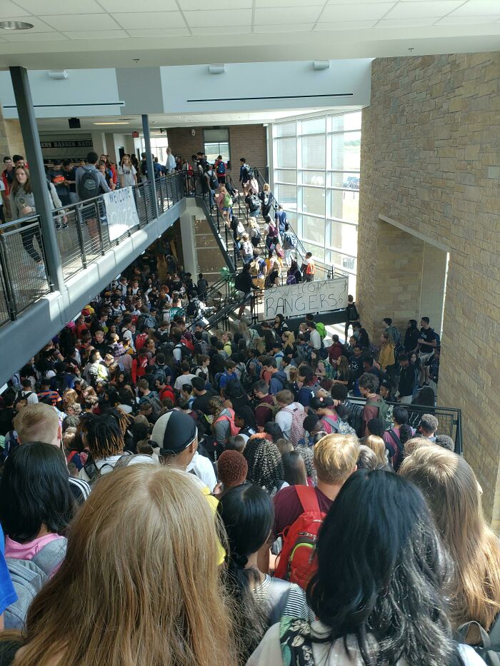 A crowded school hallway with students packed on stairs and landings, a construction fail.