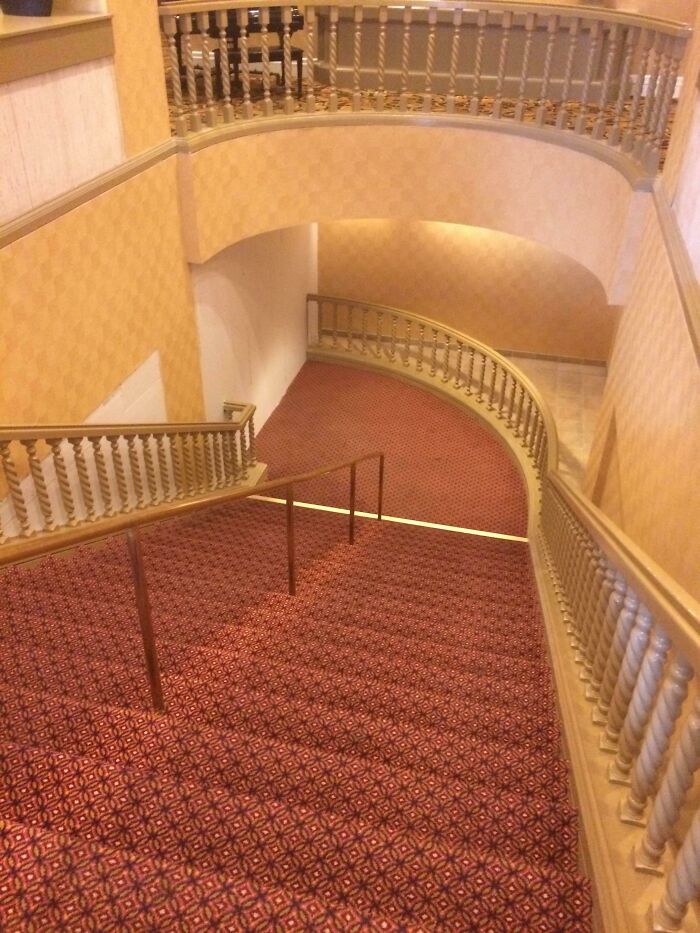 A grand staircase featuring a construction fail: a handrail that abruptly ends mid-stairs.