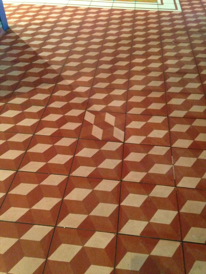 Floor tiles with a 3D cube pattern, but one tile is misaligned, showcasing a construction fail.