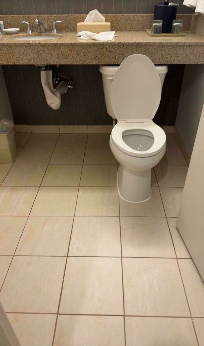 A poorly installed toilet positioned under a bathroom counter, a clear construction fail.