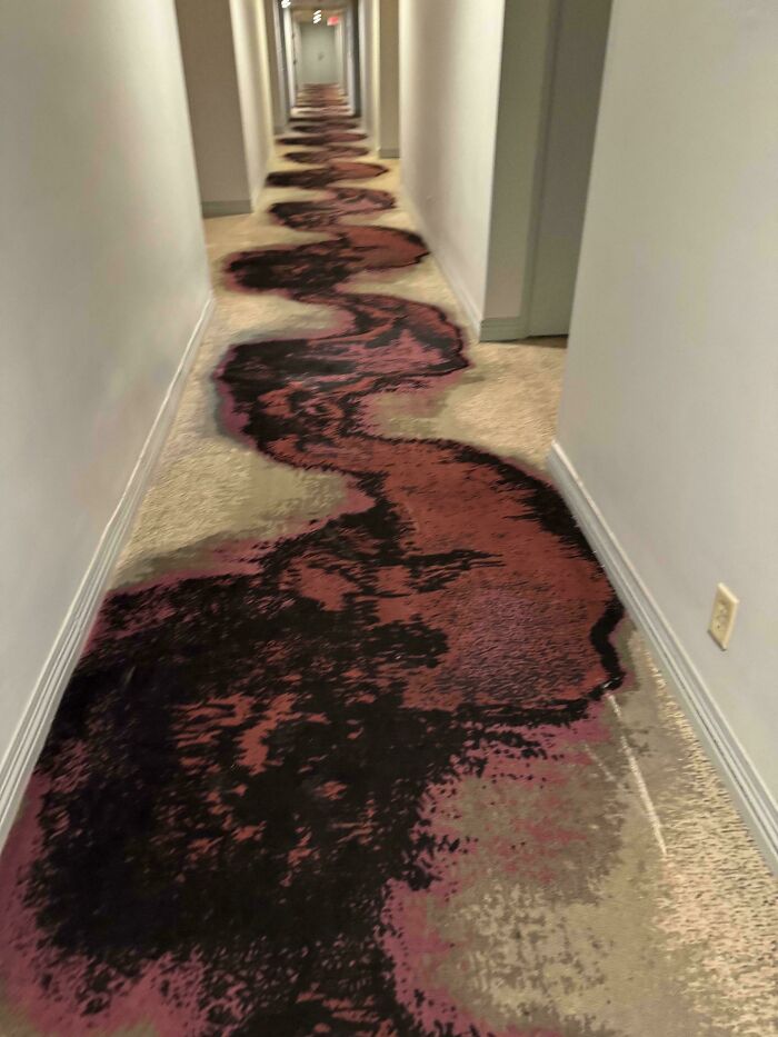 A hallway with a carpet pattern resembling a spilled, dark liquid, an unusual construction fail.