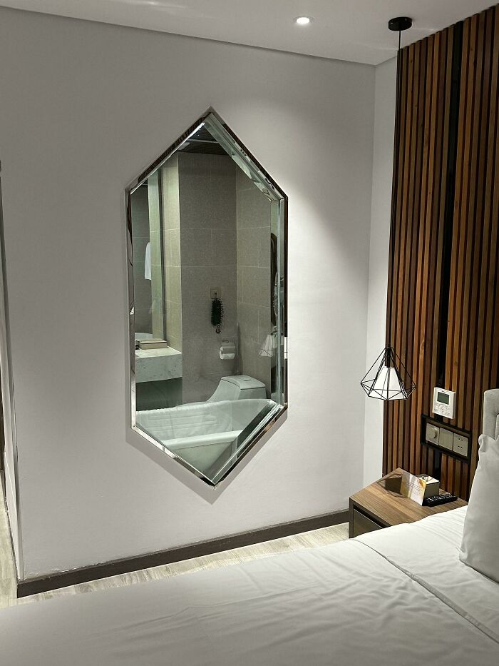 A mirror reflecting a bathroom and toilet, placed in a bedroom, a clear example of construction fails in room planning.