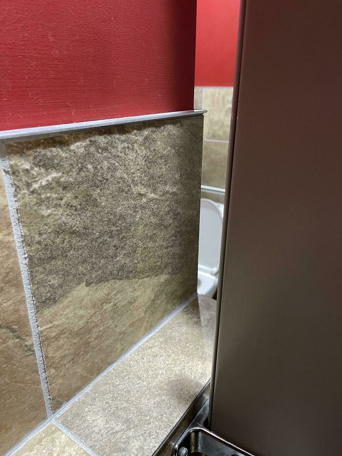 An example of a construction fail with misaligned bathroom tiles and a toilet stall.