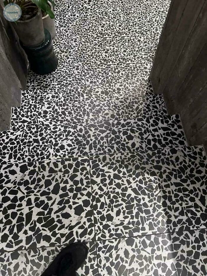 A floor with black and white patterned tiles leading down steps, where the pattern does not align, a construction fail.