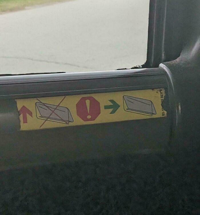 A yellow sticker on a car door with symbols indicating how to operate a window, a classic construction fail.