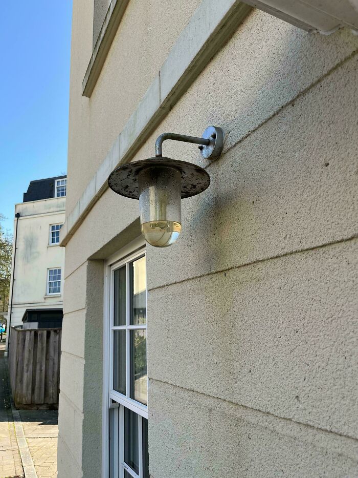 A construction fail, an outdoor light fixture is filled with water, showcasing poor installation.