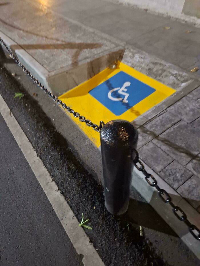 A construction fail, a disabled access ramp is blocked by a bollard and chain, rendering it unusable.
