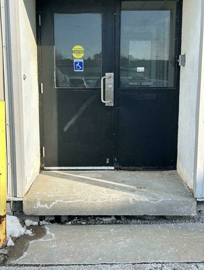 A construction fail, a door with a wheelchair access sticker has a significant step, hindering accessibility.