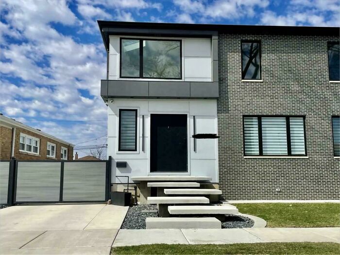 A modern house with a mix of brick and white siding, showing a clear construction fail with misaligned steps.