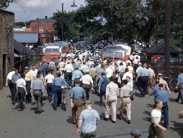 A crowded street scene with many people walking, two buses, and buildings in the background, captured in historical photos.