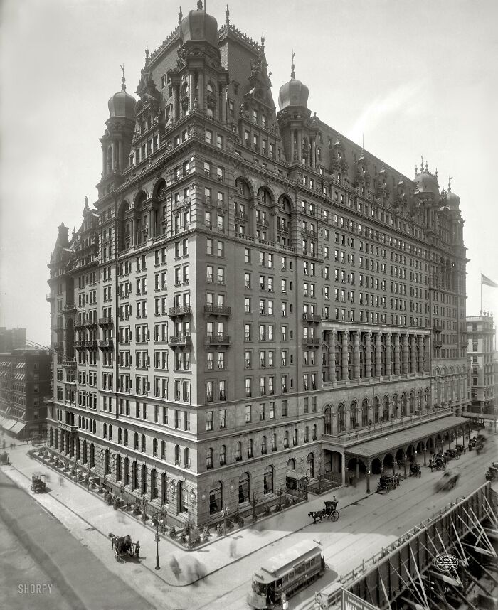 Historical photos: An ornate, grand building stands tall on a city street with horse-drawn carriages, a glimpse of the past architecture.