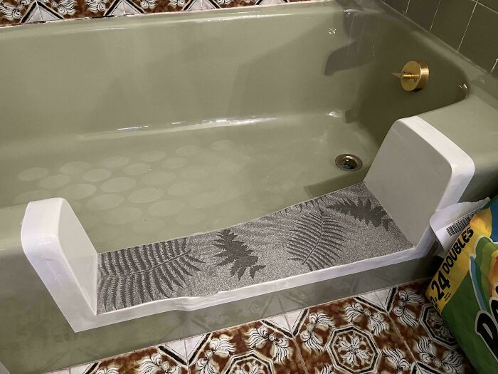An old bathtub with a temporary non-slip mat, showing people asking for help fixing things like bathroom safety.