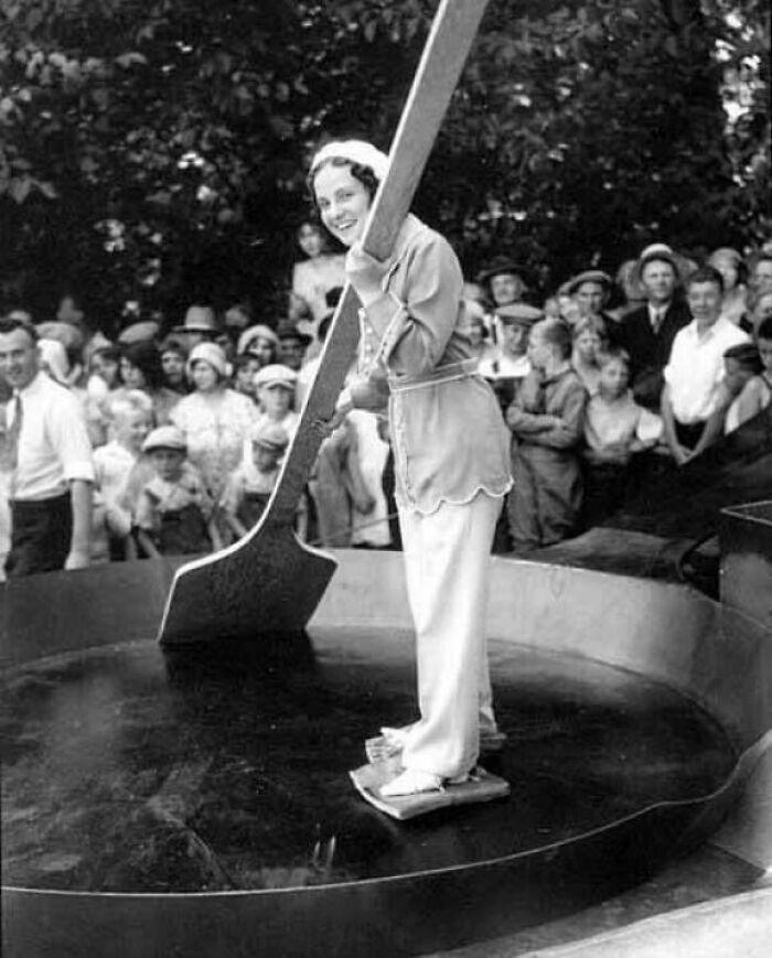 A historical photo shows a woman stirring a giant pot with an oversized spoon for a crowd, a fun past event.