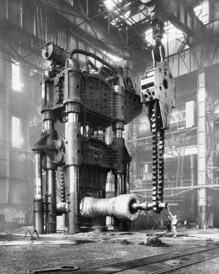 A massive industrial press with a crane in a factory in a historical photo, capturing a past era of manufacturing.