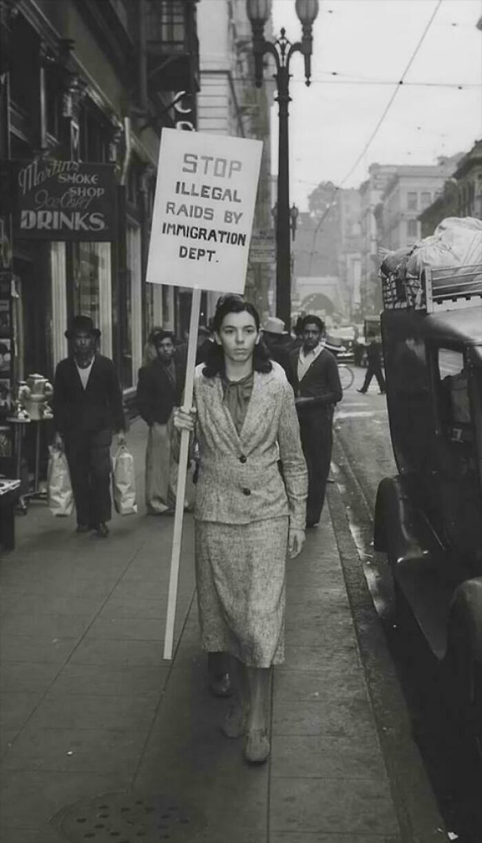 A woman holding a protest sign on a street in a historical photo, showcasing a past social movement.