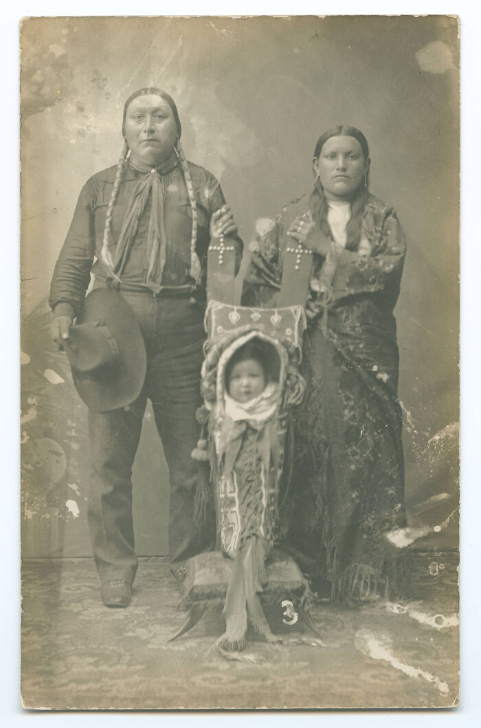 Historical photo of a Native American family with a baby in a cradleboard, showcasing a past culture.