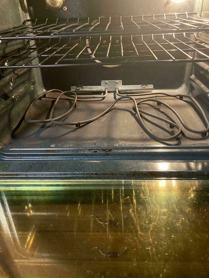 Inside view of a dirty oven with a detached heating element, highlighting the need for help fixing things.