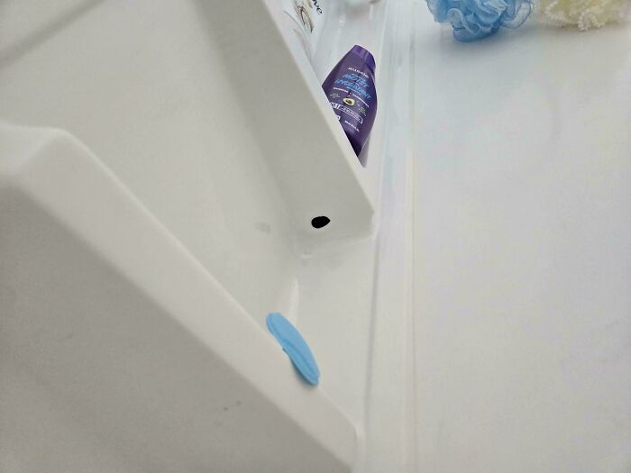 A white shower caddy with a purple bottle of shampoo and a blue sponge, revealing a common household item that needs help fixing things.