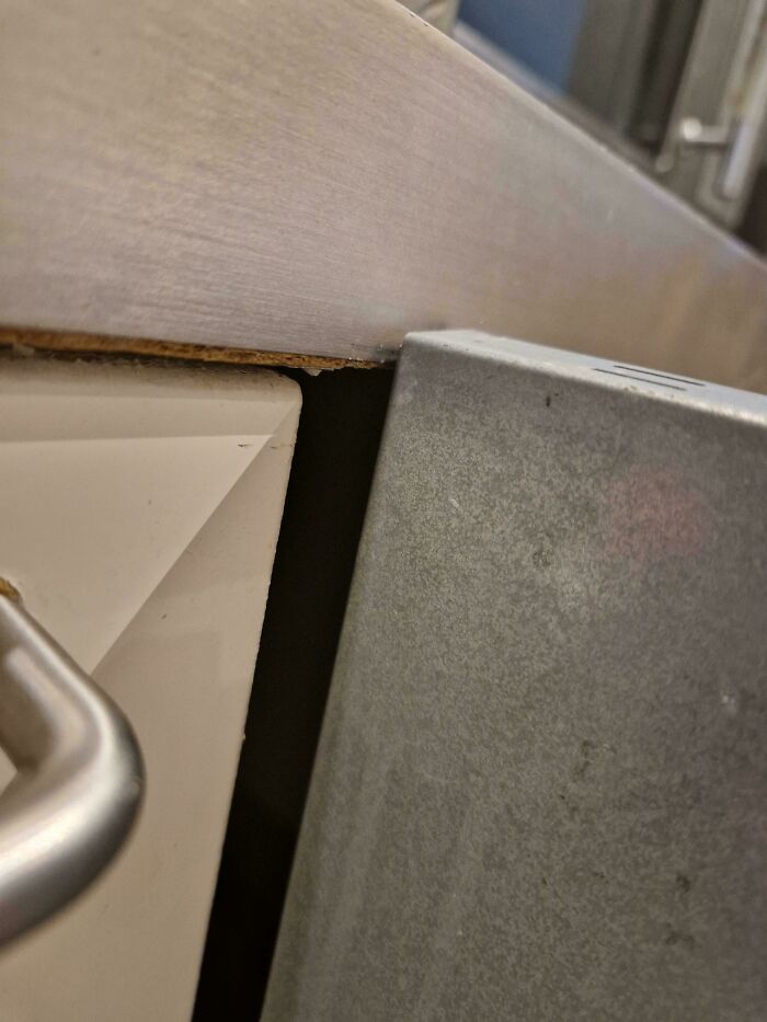A close-up of a broken counter and wall, showing a gap that needs fixing things.
