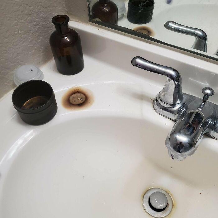 A bathroom sink with a rusted spot near the faucet, indicating a common household problem that people often ask others for help fixing.