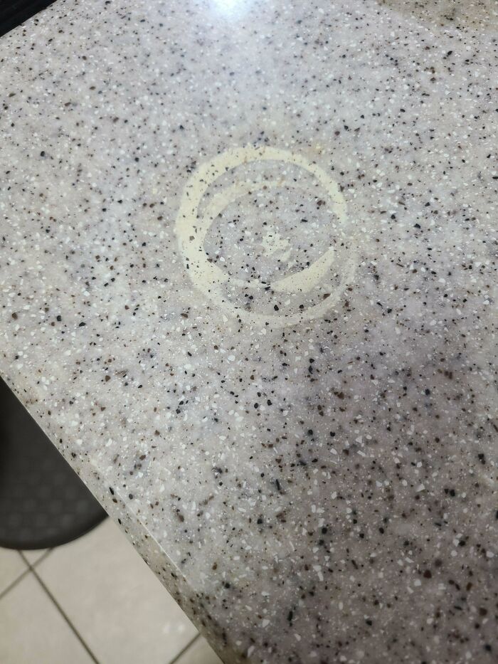 A distinct circular stain on a speckled kitchen countertop, an example of problems to be fixed.