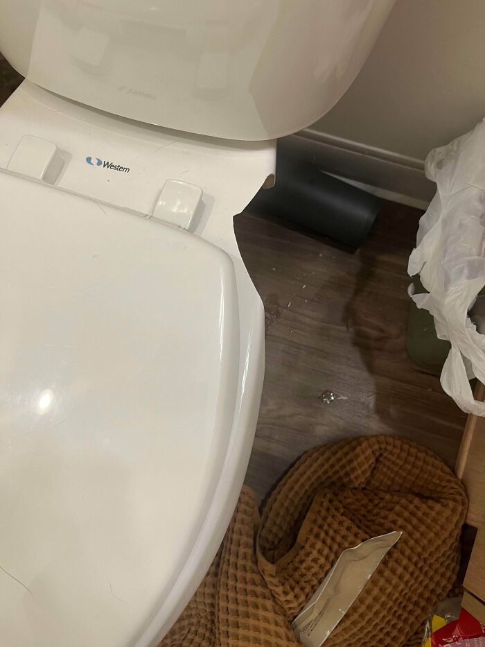 A white toilet with a broken seat, revealing a gap where something is missing, a frequent problem people ask others for help fixing things.