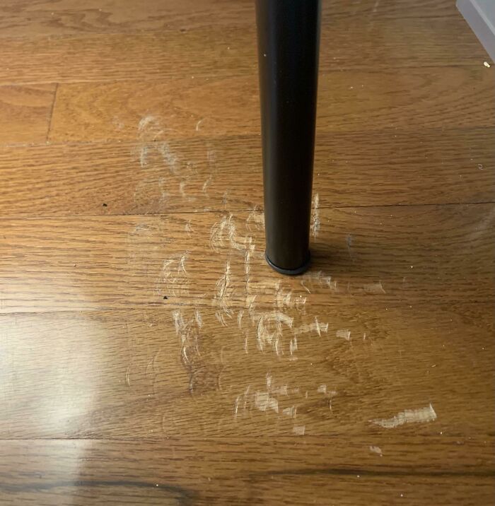 Scuff marks and residue on a wood floor around a table leg, illustrating a common problem people ask others for help fixing things.