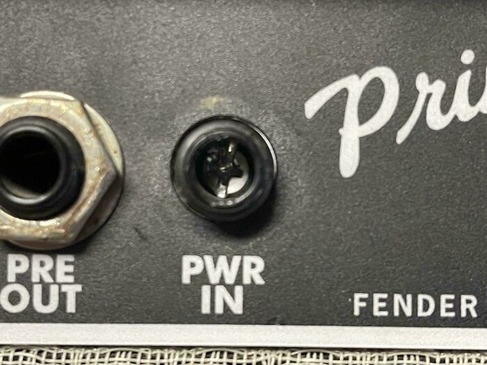 A close-up of an amplifier's back panel, showing the PWR IN jack and other connections, highlighting a problem to fix.