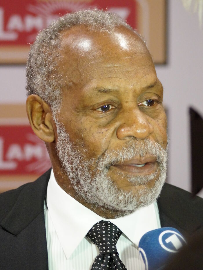 Close-up of Danny Glover, an actor known for his illustrious career highlights, speaking into a microphone.
