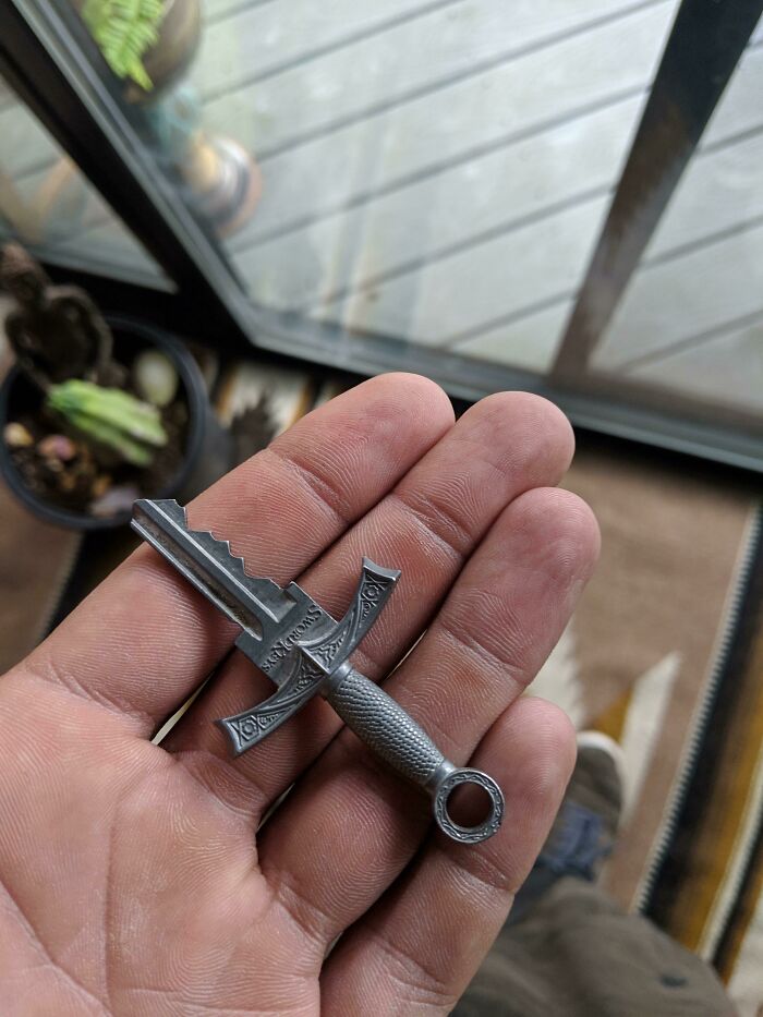 A hand holding a key that designers transformed into a sword, making ordinary things enjoyable with brilliant design.