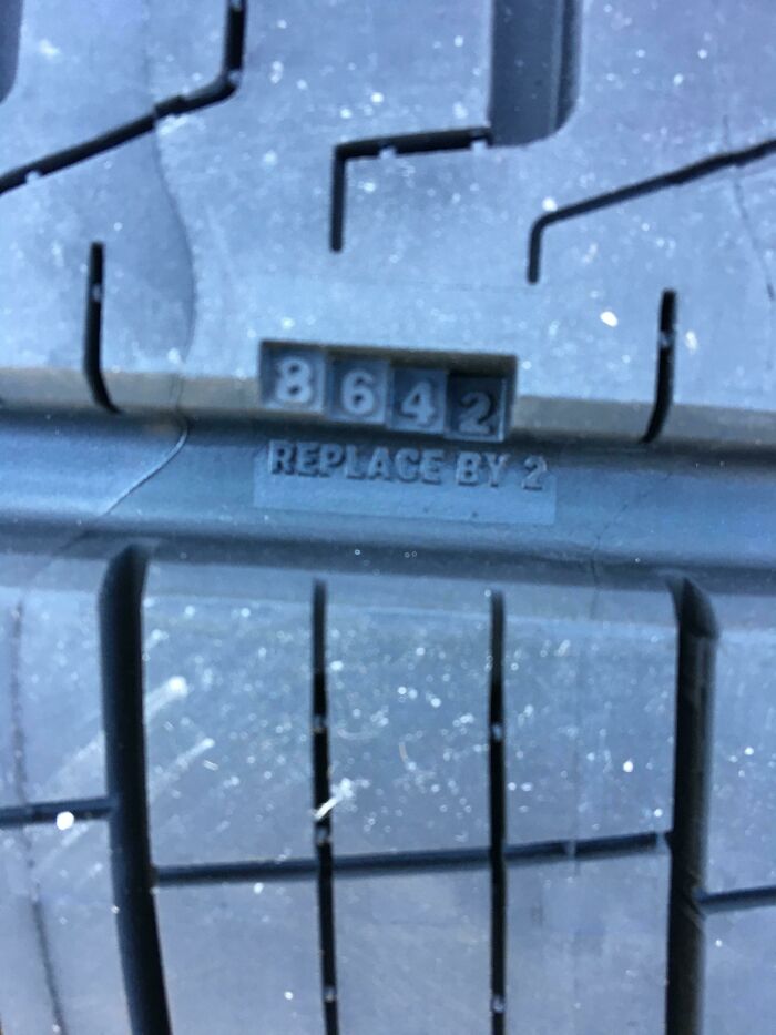 Tire with an innovative design showing wear indicator numbers 8, 6, 4, 2 and a REPLACE BY 2 mark.
