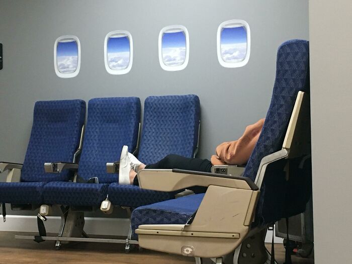 A person relaxing in a reclined airplane seat with four windows, a designer's brilliant transformation of an ordinary thing.