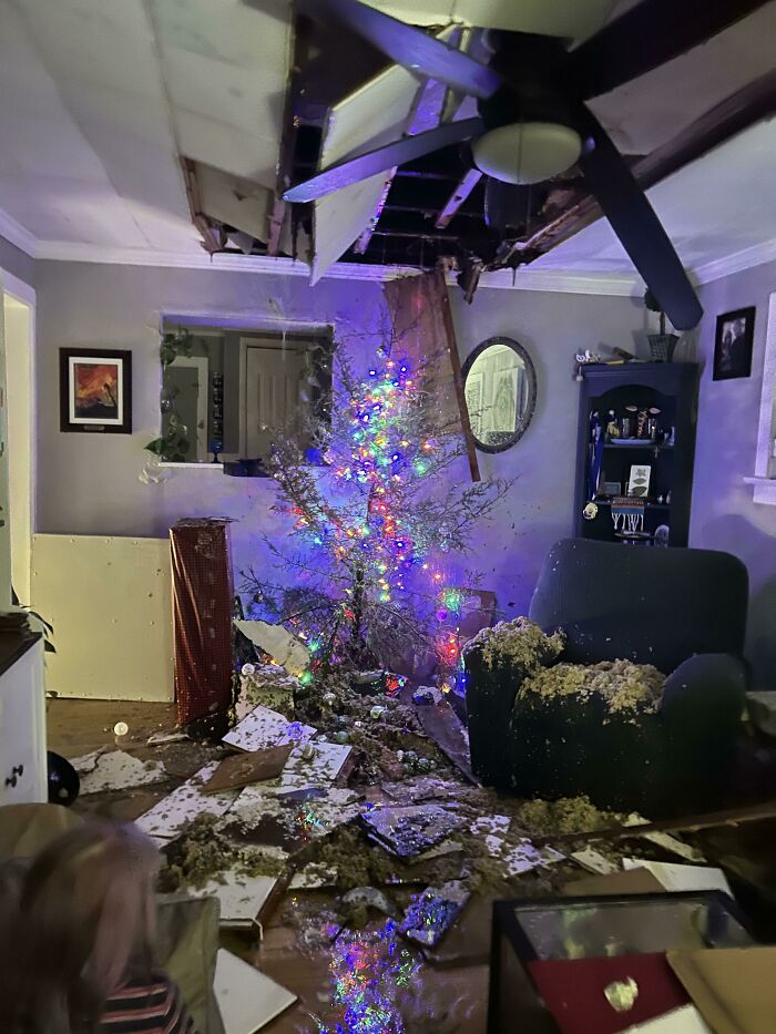 A christmas tree amidst a damaged room with a collapsed ceiling and debris, showing a worse day.