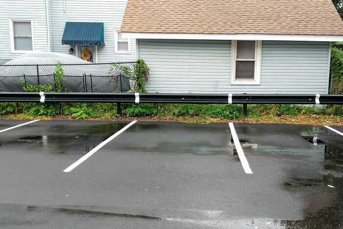 A parking lot with spaces too short due to a guard rail. Designers made using this ordinary thing unenjoyable.