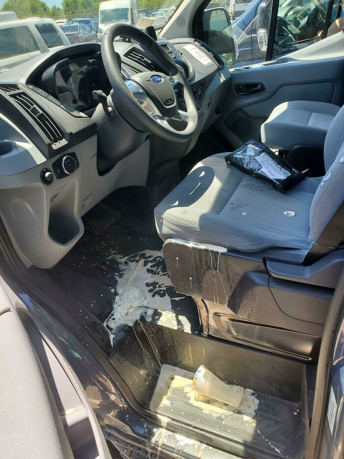 Spilled paint covers the floor and seat of a car. Someone is having a worse day.