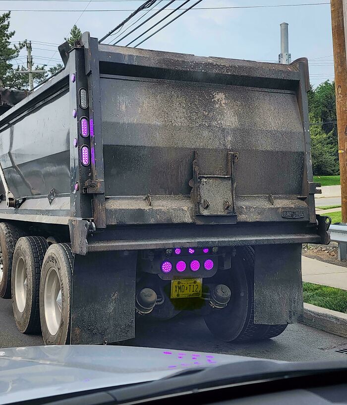 A large dump truck with striking purple lights on the back, a brilliant transformation of ordinary things.