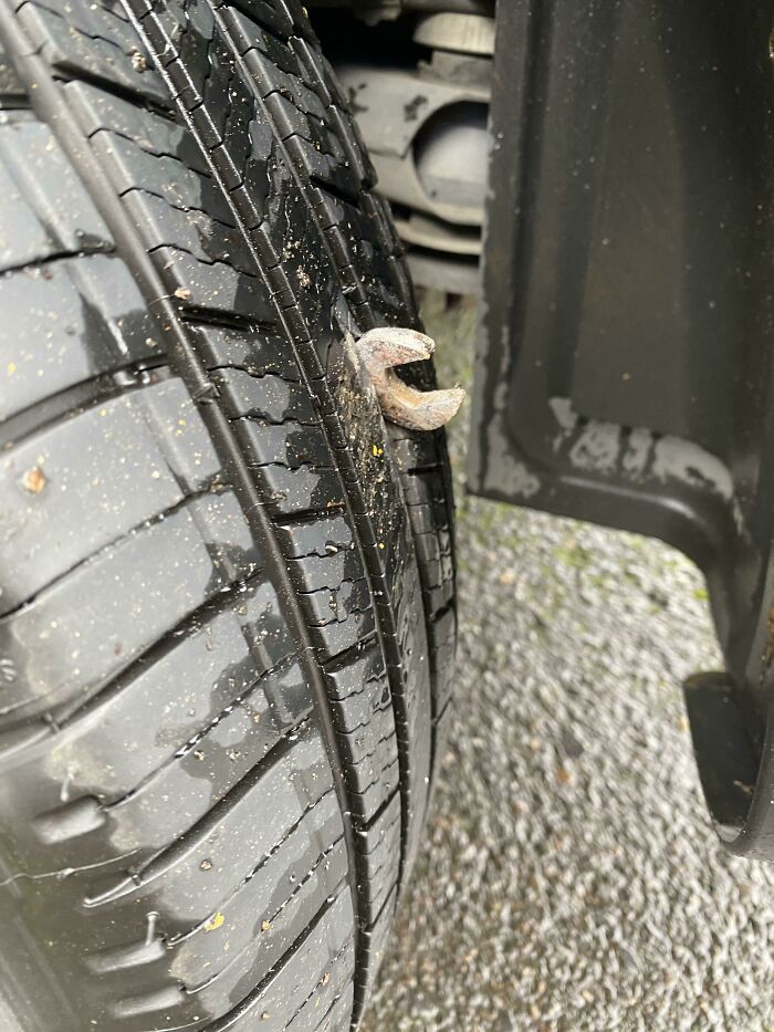 A large, rusty nail puncturing a car tire, illustrating a way worse day.