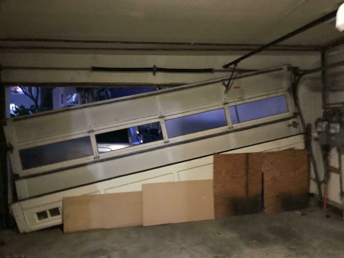 A garage door hanging crookedly off its tracks, signaling a really worse day.