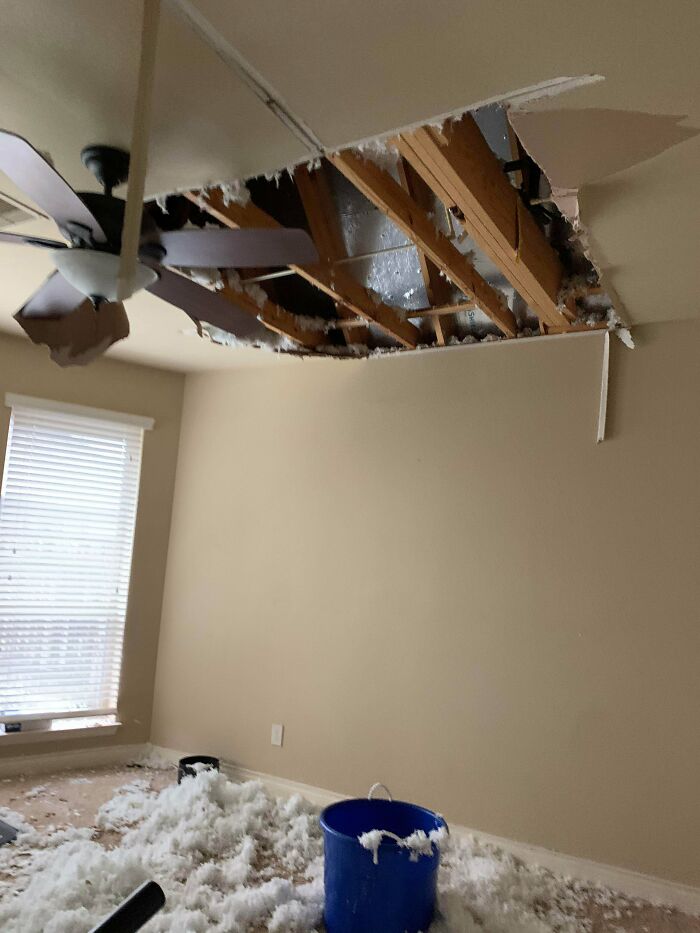 A collapsed ceiling with insulation scattered on the floor and a blue bucket, indicating a worse day.