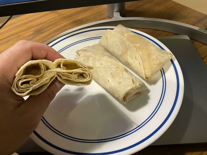 A person holding a poorly wrapped burrito, revealing only tortilla, illustrating a worse day.